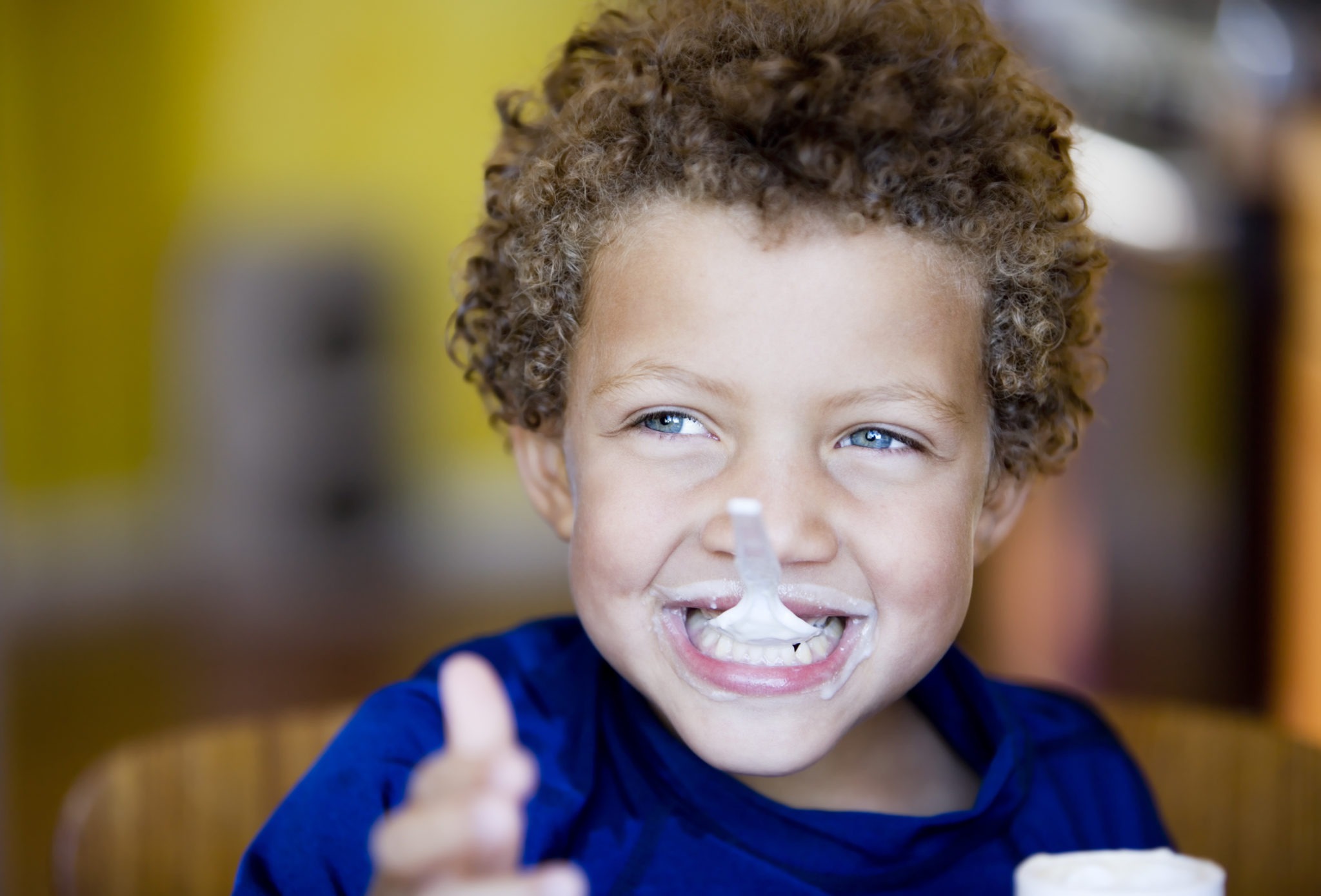 Boy with blue eyes eating yogurt